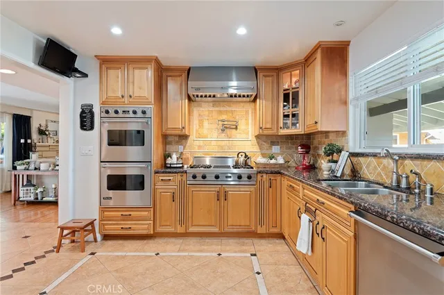 a kitchen with stainless steel appliances granite countertop a stove top oven a sink a dining table and chairs