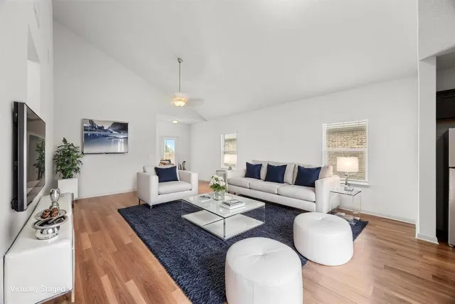 a living room with furniture a flat screen tv and a wooden floor