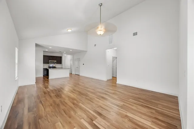 a view of empty room with wooden floor and window
