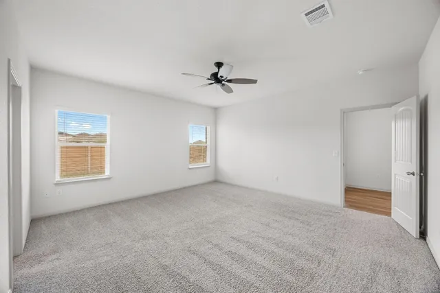 an empty room with windows and fan