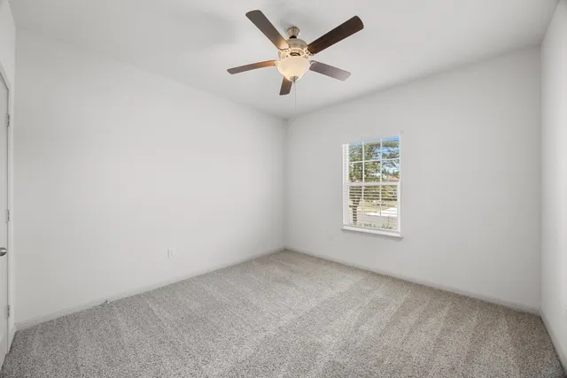 an empty room with a window and a ceiling fan