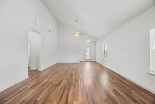 a view of empty room with wooden floor and fan