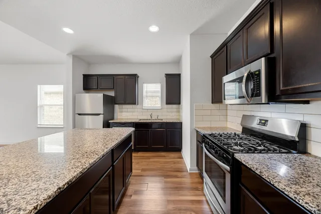 a kitchen with stainless steel appliances granite countertop a sink stove microwave and cabinets
