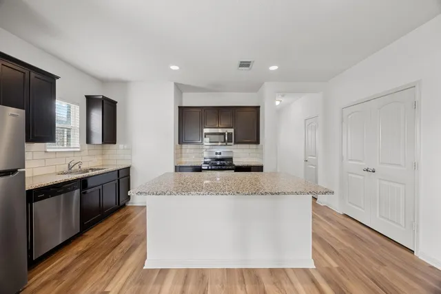 a large kitchen with stainless steel appliances a large counter top a stove and a sink