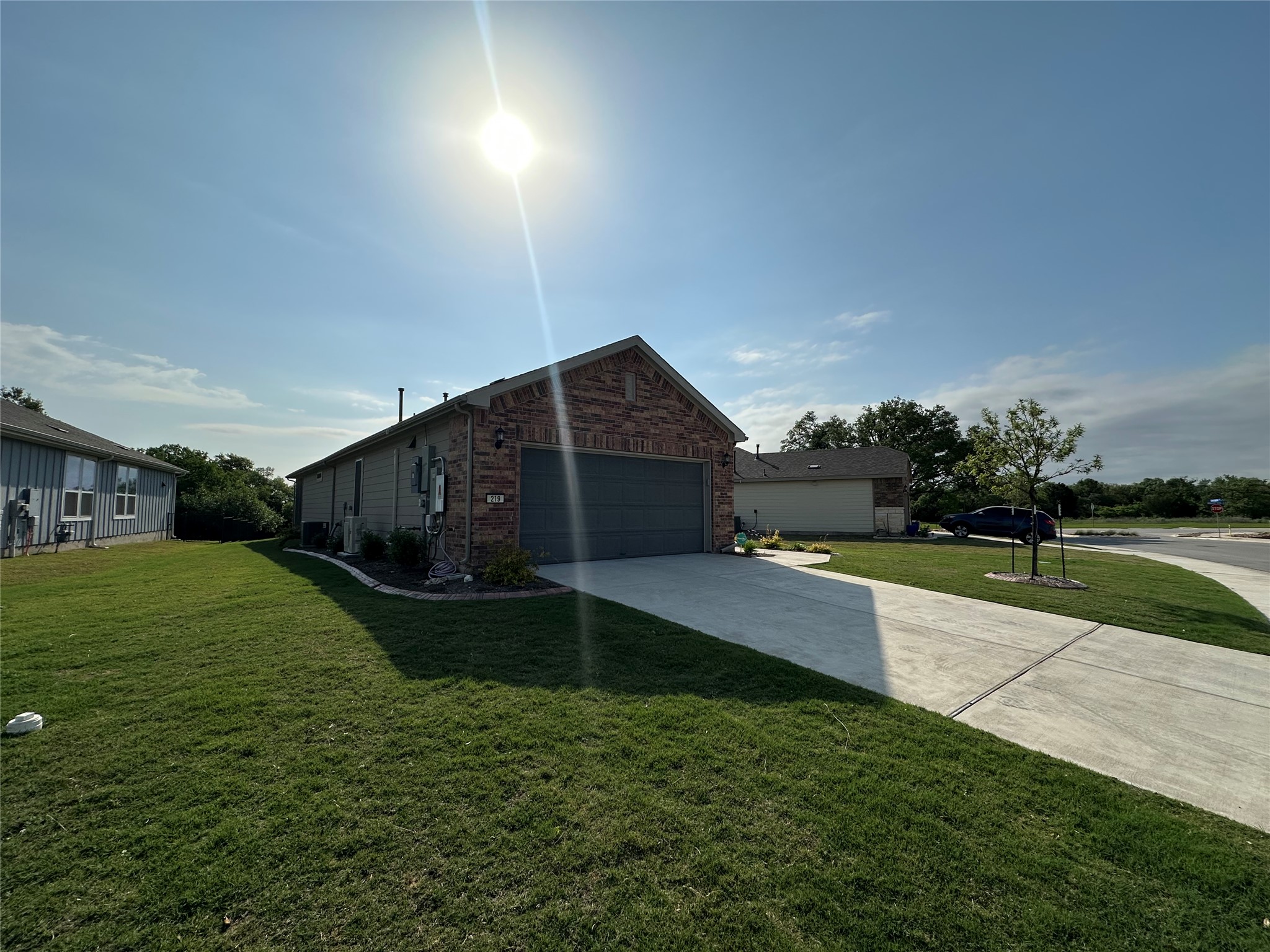 View of home's exterior with brick siding, a lawn, a garage, and concrete driveway
