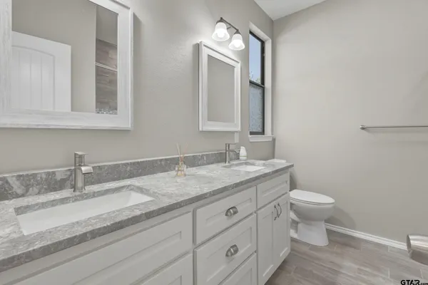a bathroom with a granite countertop sink a toilet and a mirror