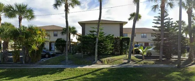 a view of a house with a yard and palm trees
