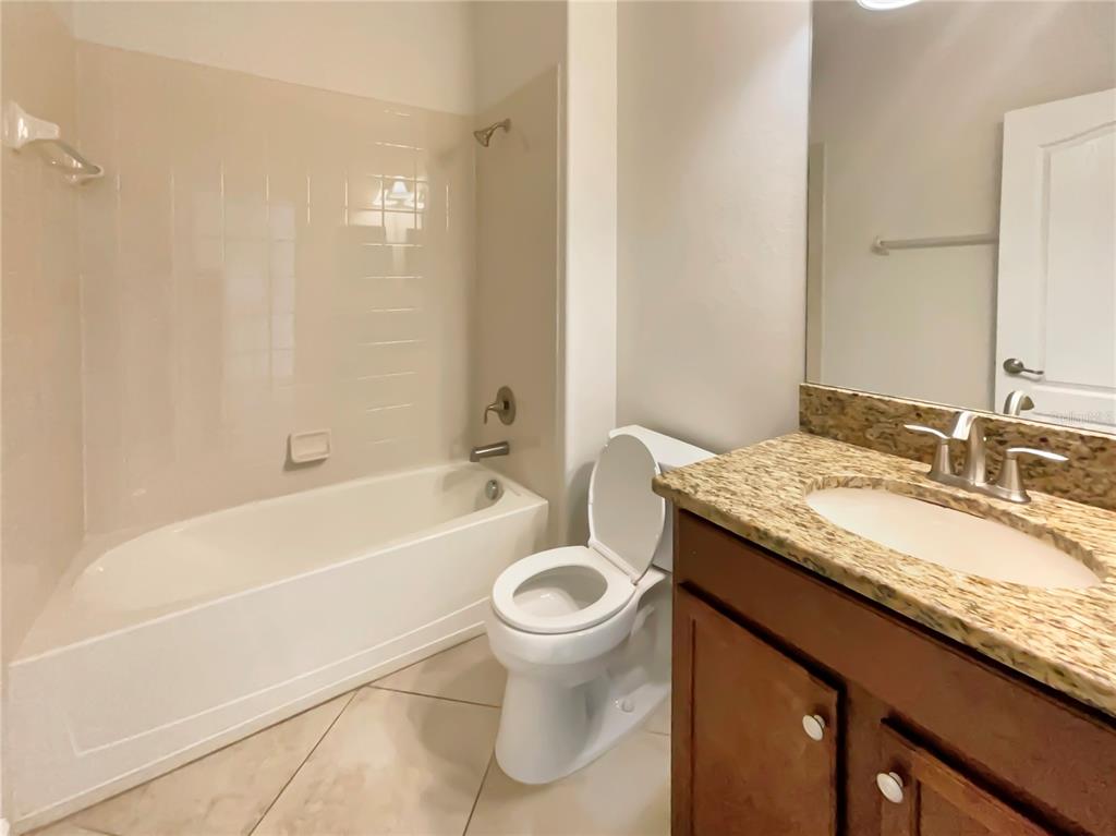19491 Paddock View Drive Tampa, FL 33647 - Photo 12 of 28 a bathroom with a granite countertop sink a toilet and a bathtub