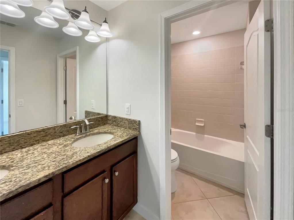 19491 Paddock View Drive Tampa, FL 33647 - Photo 25 of 28 a bathroom with a granite countertop sink and a mirror