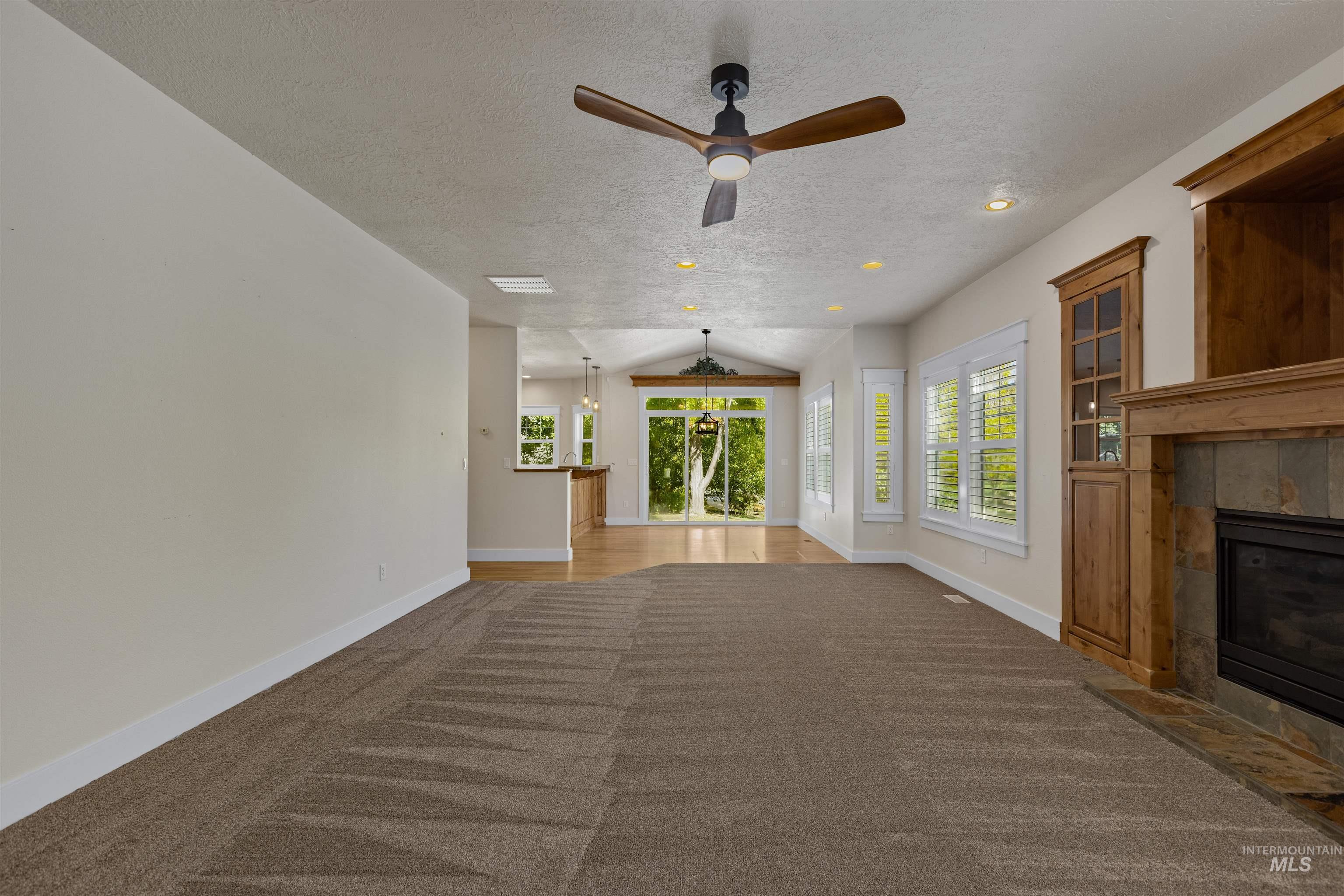 5426 West School Ridge Road Boise, ID 83714 - Photo 16 of 39 Recessed lighting and a ceiling fan, bay windows with plantation shutters, a fireplace with stone surround, and custom built-in cabinetry