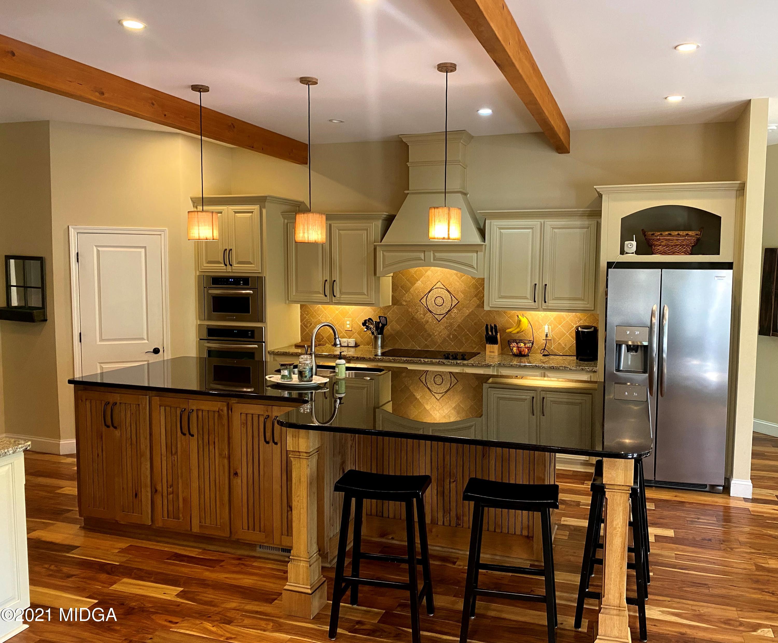 619 Harper Road Perry, GA 31069 - Photo 25 of 27 a kitchen with stainless steel appliances kitchen island granite countertop a table chairs in it and wooden floors
