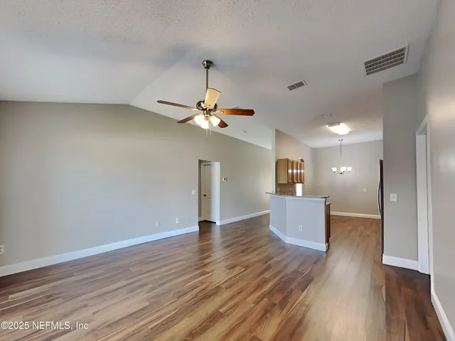 a view of a room with wooden floor and ceiling fan