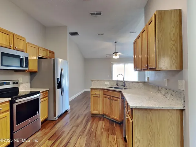 a kitchen with stainless steel appliances a sink cabinets and wooden floor