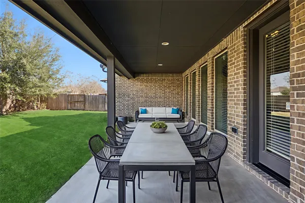 a view of a dining table and chairs in back yard of a house