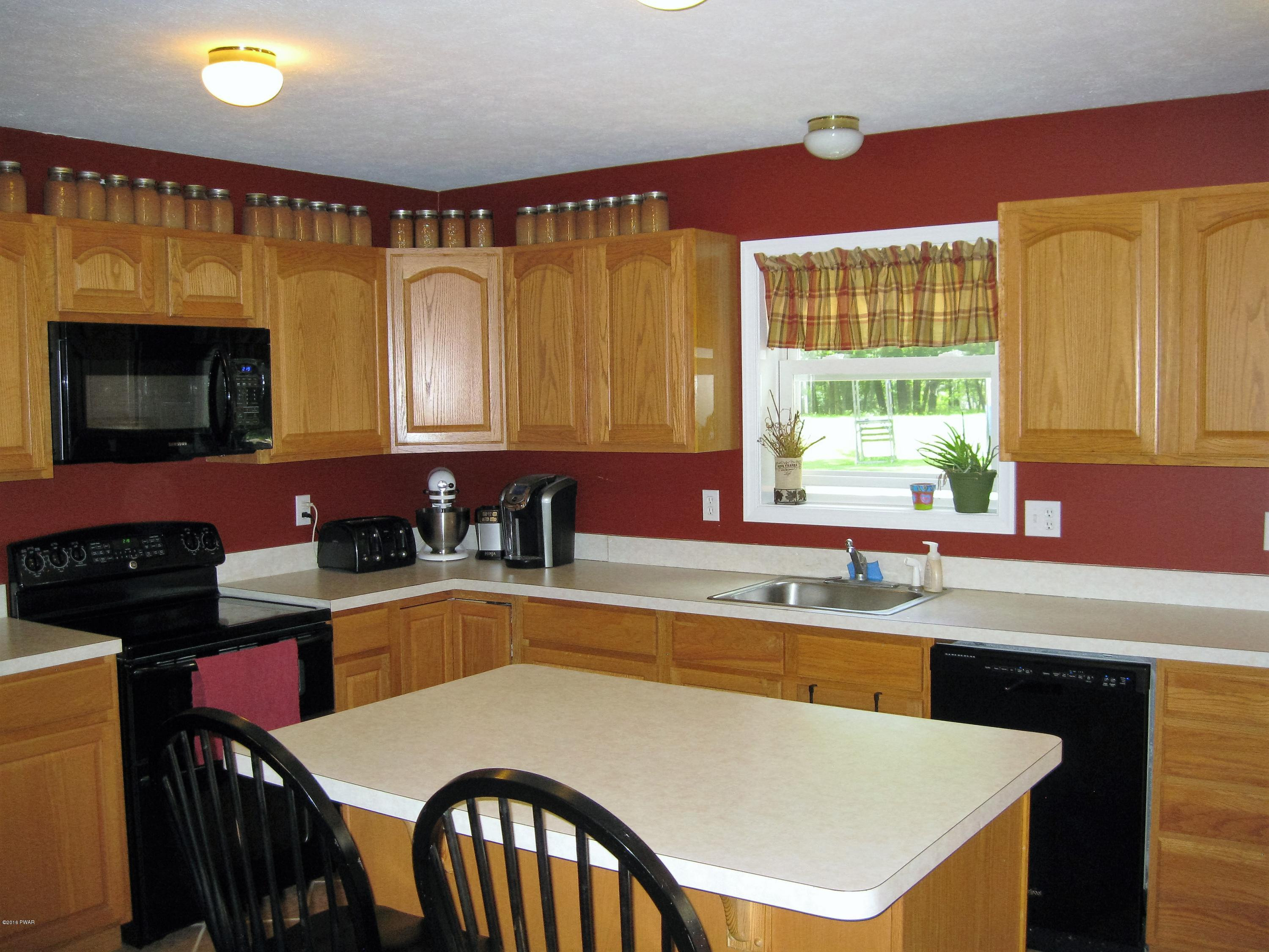 137 Caribou Road Dingmans Ferry, PA 18328 - Photo 11 of 34 a kitchen with a stove a sink a dining table and chairs