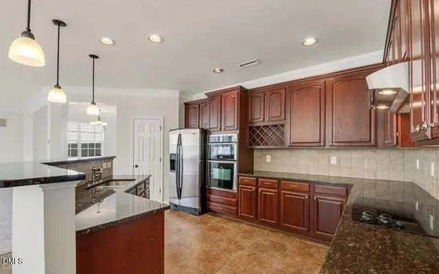 a kitchen with kitchen island granite countertop wooden cabinets a stove a sink and a refrigerator