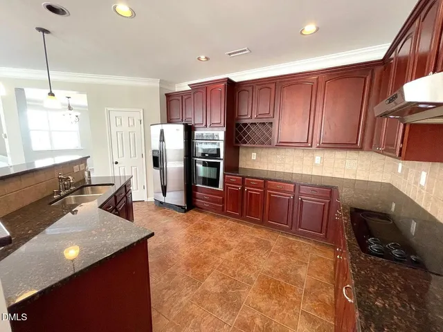 a kitchen with stainless steel appliances a stove a refrigerator and a sink with wooden cabinets