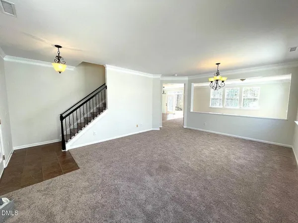 a view of an empty room with window and stairs