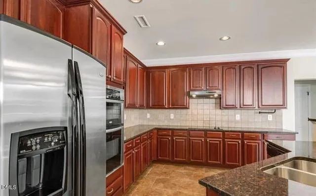 a kitchen with stainless steel appliances granite countertop a refrigerator and a stove top oven