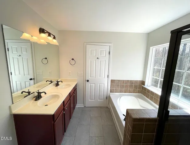 a spacious bathroom with a bathtub sink and mirror
