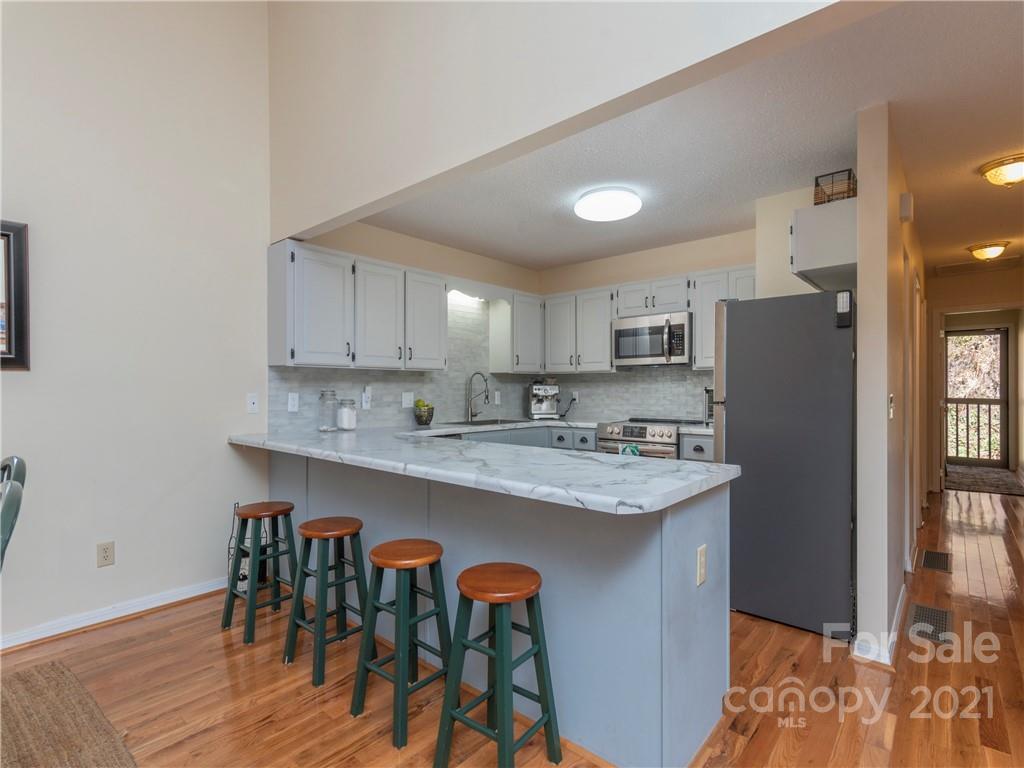 51 Forest Road Canton, NC 28716 - Photo 7 of 26 a kitchen with stainless steel appliances granite countertop a refrigerator a sink a stove and white cabinets with wooden floor