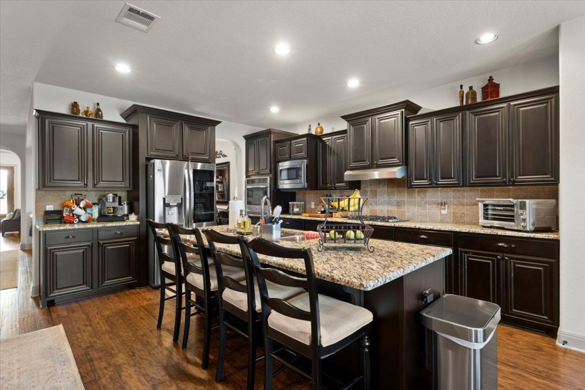 224 Whitney Woods Circle Georgetown, TX 78633 - Photo 12 of 40 a kitchen with granite countertop a table chairs microwave and cabinets