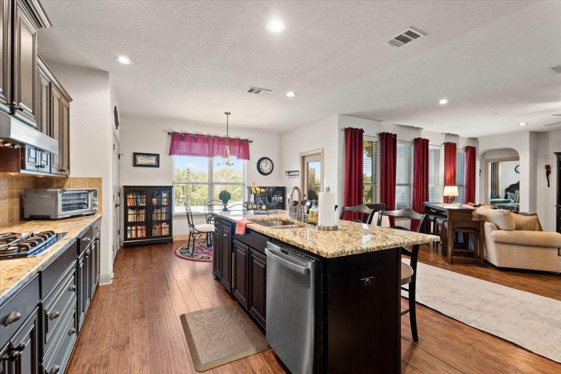 224 Whitney Woods Circle Georgetown, TX 78633 - Photo 14 of 40 a large kitchen with stainless steel appliances granite countertop a stove a sink dishwasher and a dining table with the living room view