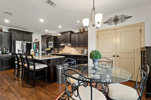 a kitchen with kitchen island a dining table chairs stainless steel appliances and cabinets