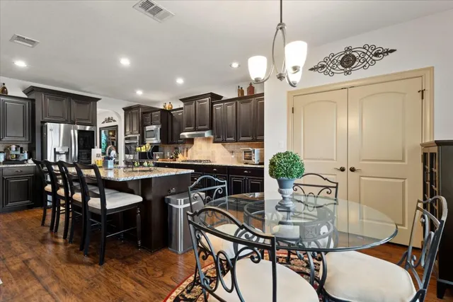 a kitchen with kitchen island a dining table chairs stainless steel appliances and cabinets