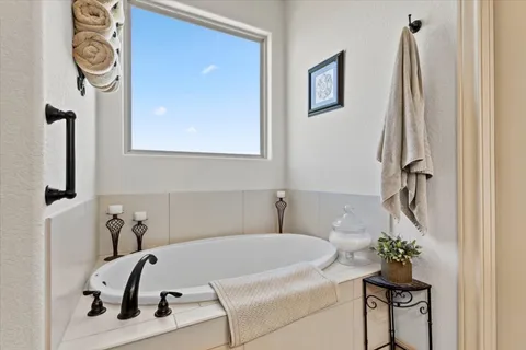 a bath tub sitting next to a white sink and a mirror