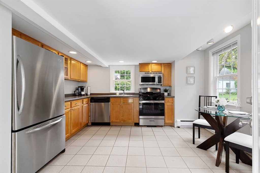 148 Wood Street, Unit 4 Lexington, MA 02421 - Photo 2 of 26 a kitchen with a refrigerator a stove top oven a sink a dining table and chairs