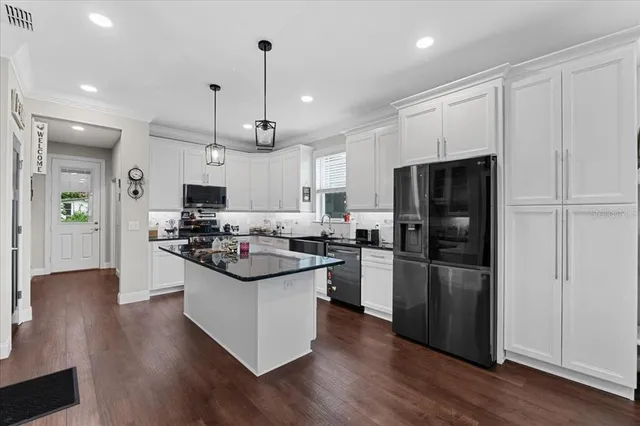 a kitchen with kitchen island white cabinets and stainless steel appliances