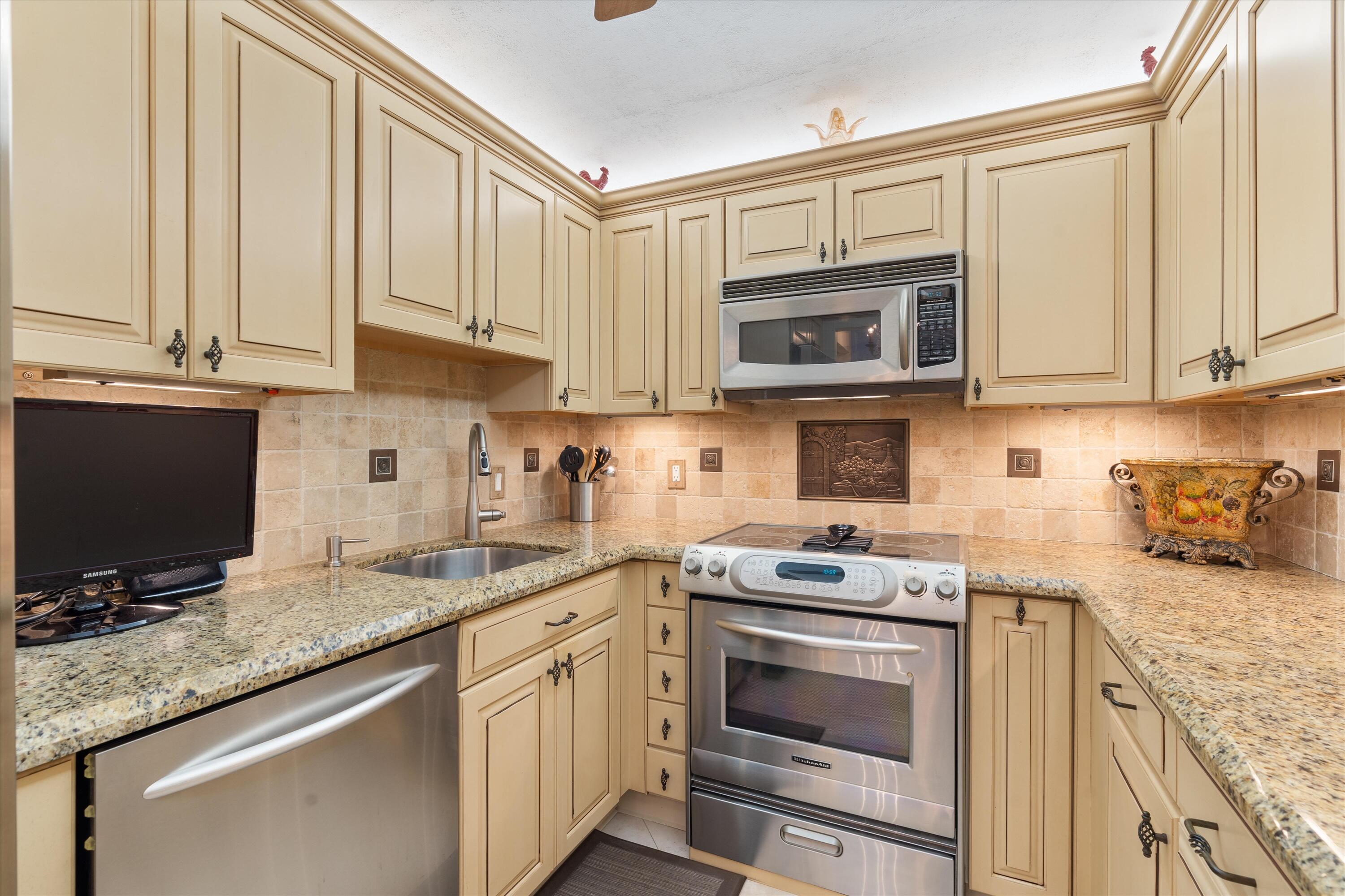 4505 South Ocean Boulevard, Unit 904 Highland Beach, FL 33487 - Photo 25 of 39 a kitchen with granite countertop a stove top oven microwave and cabinets