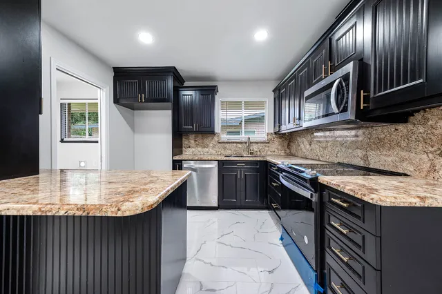 a kitchen with stainless steel appliances granite countertop a stove a sink and a microwave