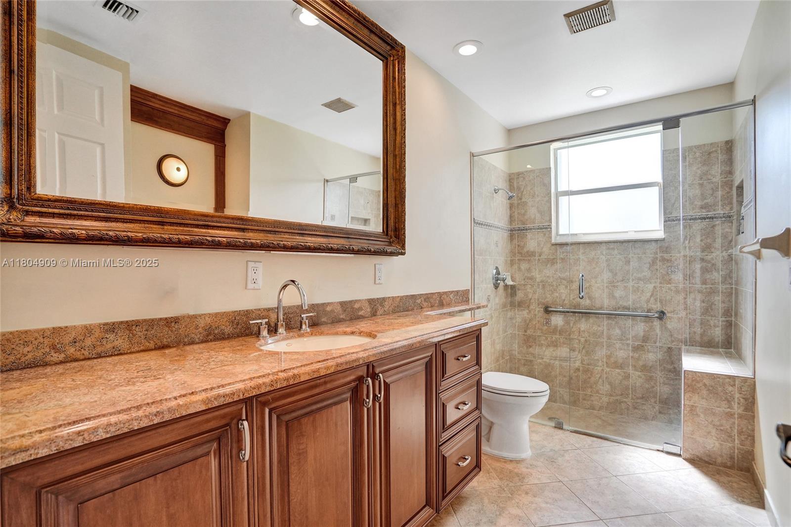 10457 Laurel Road Davie, FL 33328 - Photo 60 of 96 a bathroom with a granite countertop sink a toilet and a mirror