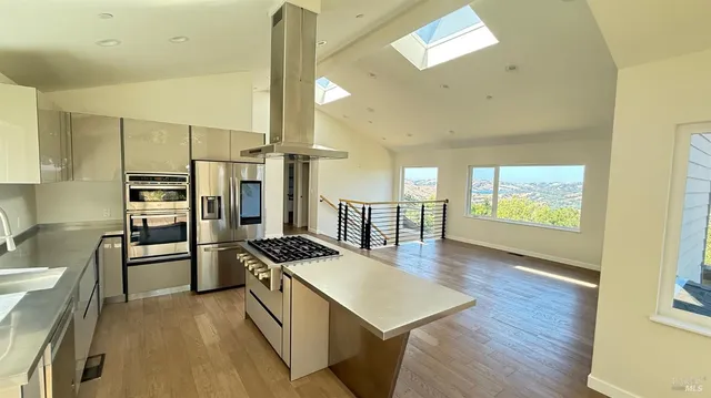 a kitchen with stainless steel appliances a stove a refrigerator and wooden floor