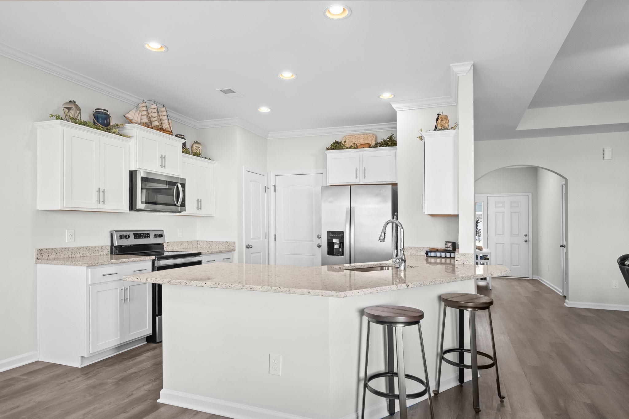 447 Honeyhill Loop Conway, SC 29526 - Photo 12 of 39 Kitchen featuring stainless steel appliances, a peninsula, white cabinets, arched walkways, and light stone countertops