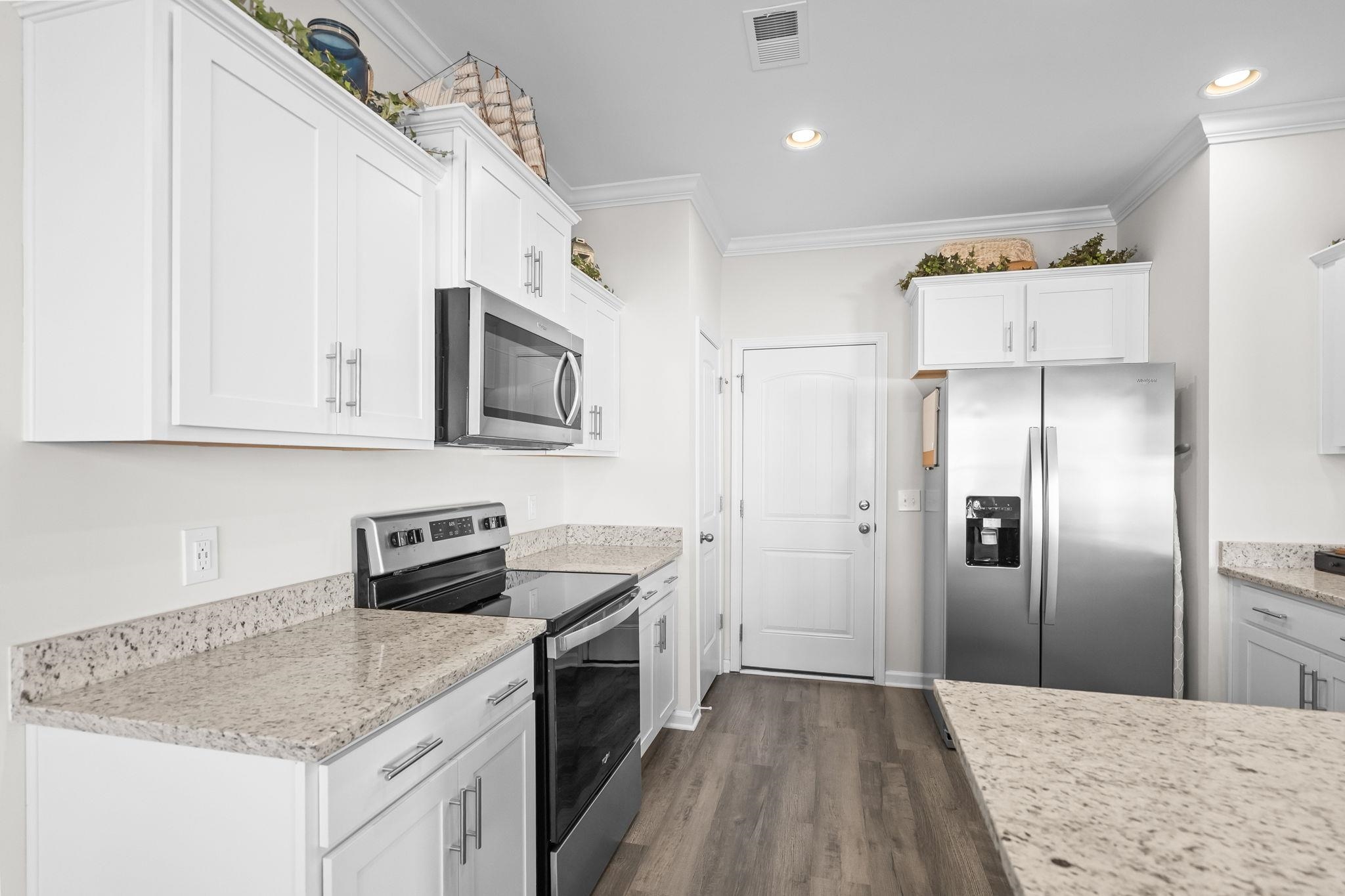 447 Honeyhill Loop Conway, SC 29526 - Photo 13 of 39 Kitchen with stainless steel appliances, ornamental molding, light stone counters, white cabinets, and dark wood-type flooring