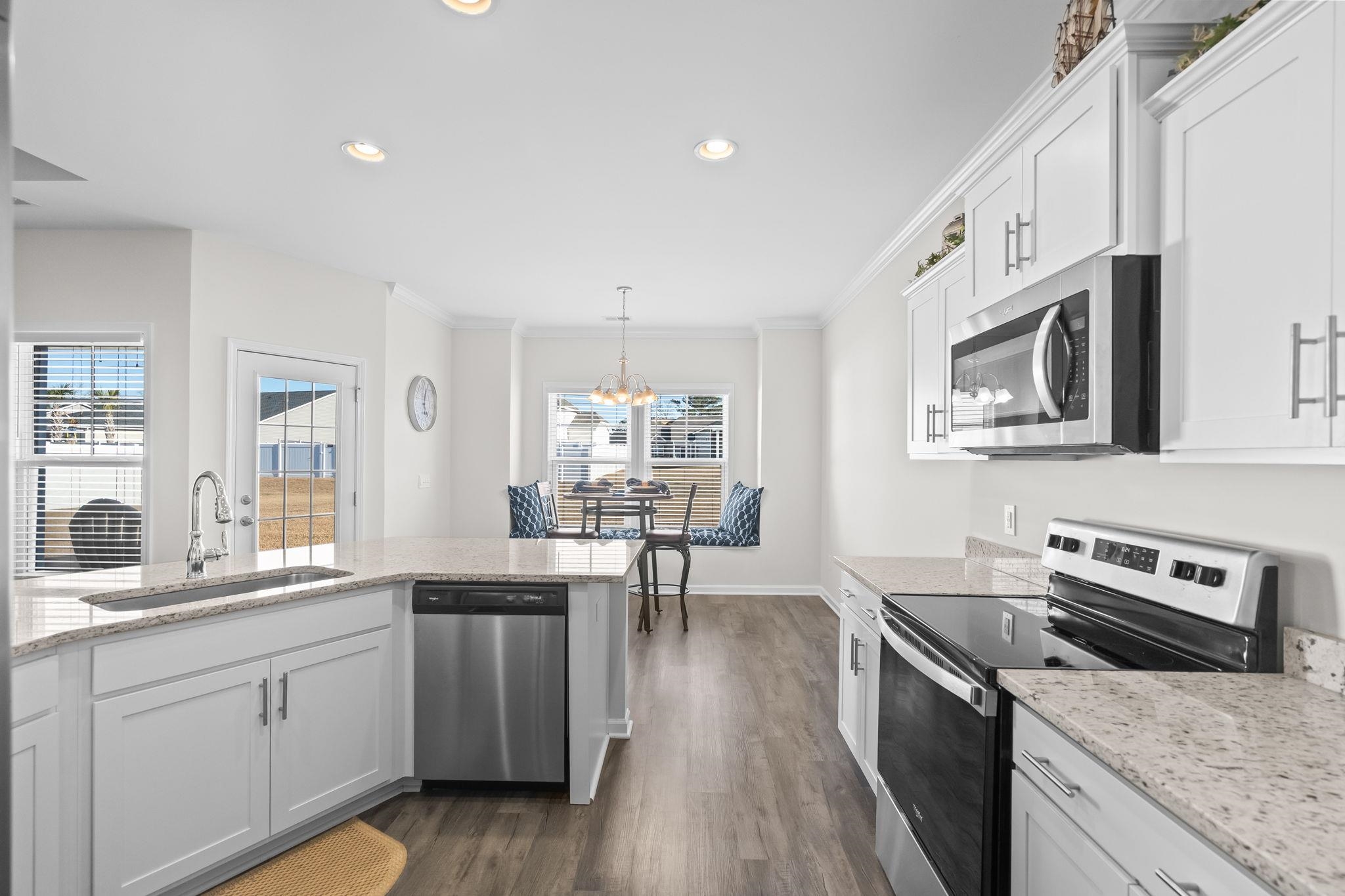 447 Honeyhill Loop Conway, SC 29526 - Photo 14 of 39 Kitchen with appliances with stainless steel finishes, white cabinets, light stone countertops, crown molding, and dark wood finished floors