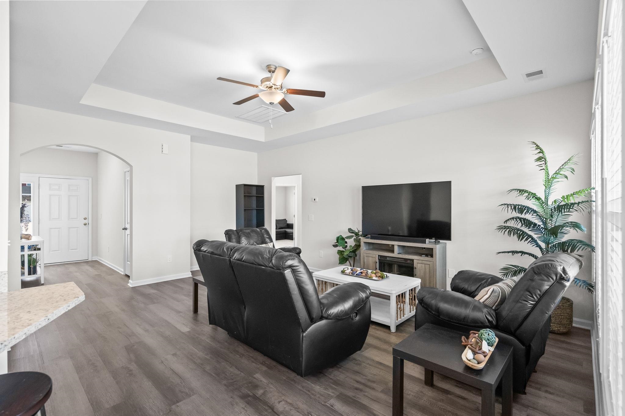 447 Honeyhill Loop Conway, SC 29526 - Photo 7 of 39 Living area featuring a raised ceiling, arched walkways, dark wood-style floors, and a ceiling fan