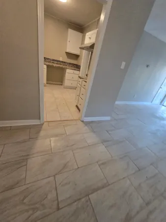a view of a refrigerator in kitchen and an empty room