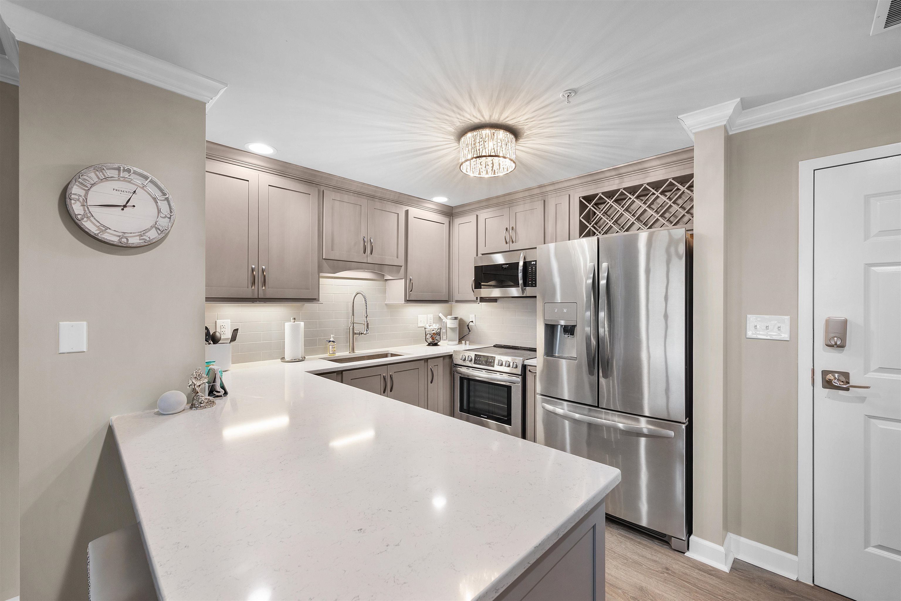 323 Cr 380 Road, Unit P 506 Iuka, MS 38852 - Photo 6 of 21 Kitchen featuring stainless steel appliances, a peninsula, decorative backsplash, light stone counters, and light wood-style floors