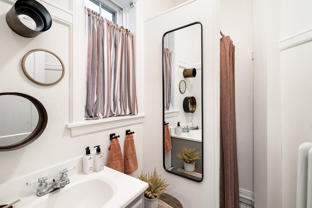 986 Memorial Drive, Unit 404 Cambridge, MA 02138 - Photo 21 of 41 a bathroom with a sink a mirror and a shower curtain
