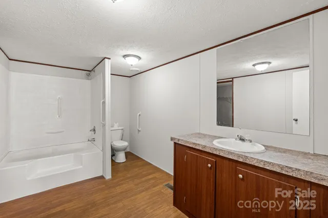 a bathroom with a granite countertop sink a toilet and shower