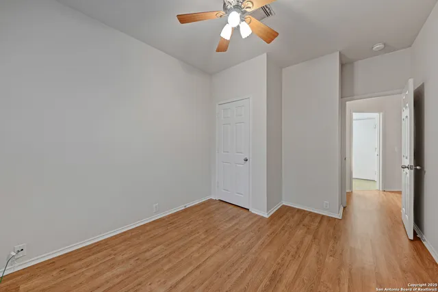 an empty room with a chandelier fan and windows