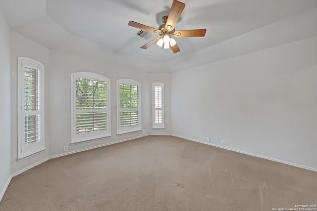 a view of an empty room with window and chandelier fan