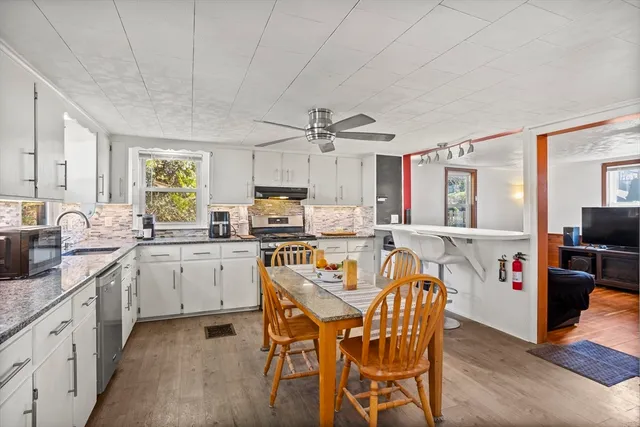 a kitchen with stainless steel appliances granite countertop a sink dishwasher stove refrigerator and cabinets with wooden floor