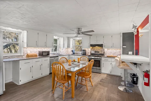 a kitchen with stainless steel appliances a table chairs and a refrigerator
