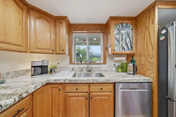 a kitchen with granite countertop stainless steel appliances a sink window and cabinets