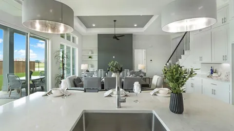 a dining room with chandelier fan and wooden floor